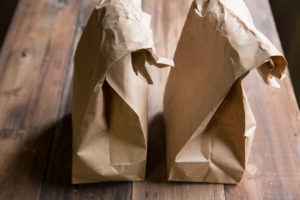 Two brown paper lunch bags on wooden table.