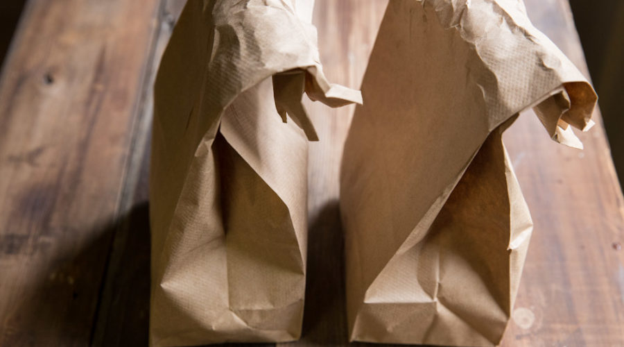 Two brown paper lunch bags on wooden table.