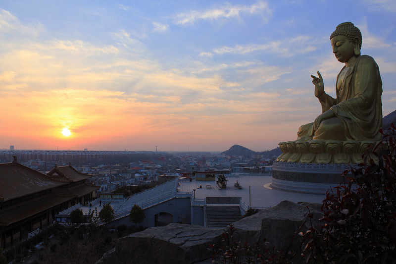 Buddha above the city at sunset