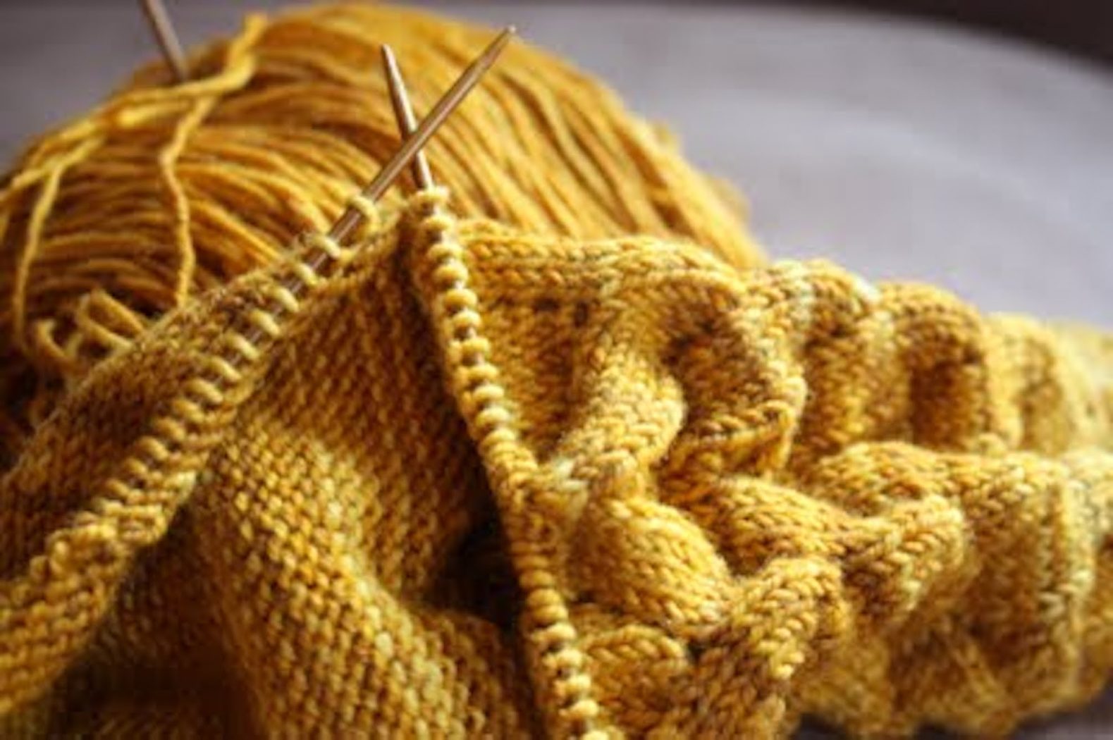 deep gold yarn with knitting needles