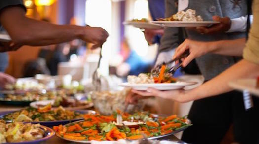 Potluck table with people serving