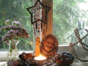 Windowsill altar with candle, berries, and Maharaji