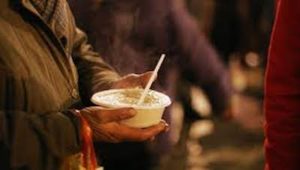 man holding a bowl of soup outdoors