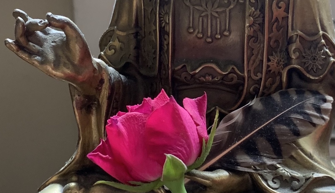 Hand of Buddha with rose bud and feather